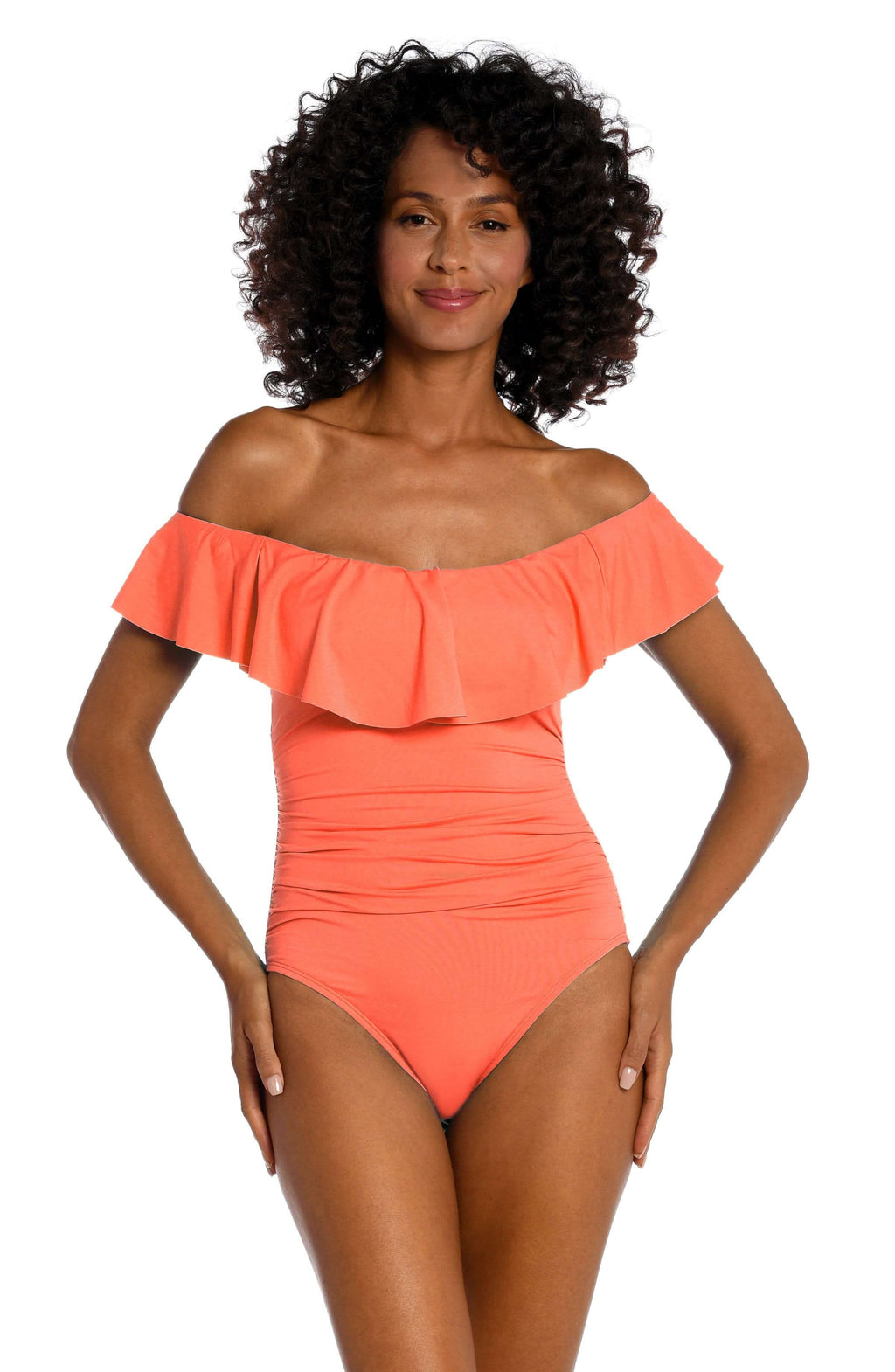 Front image of model wearing a solid coral colored one piece swimsuit featuring a ruffle front and strapless design. 