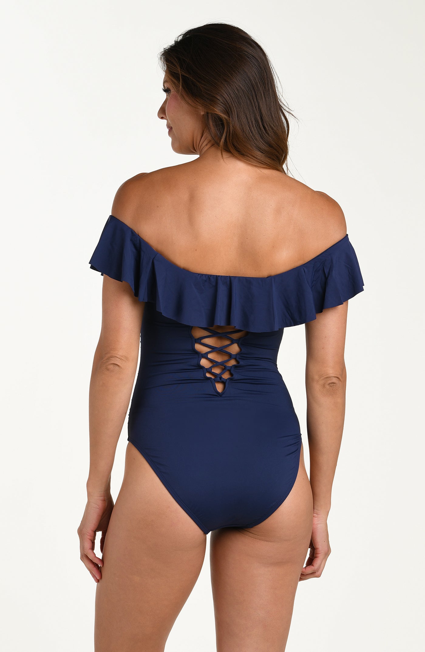 
                  
                    Back image of model wearing an indigo (navy blue) colored off-the-shoulder one-piece swimsuit featuring a ruffle neckline, a lace-up back detail for adjustable fit and moderate rear coverage.
                  
                