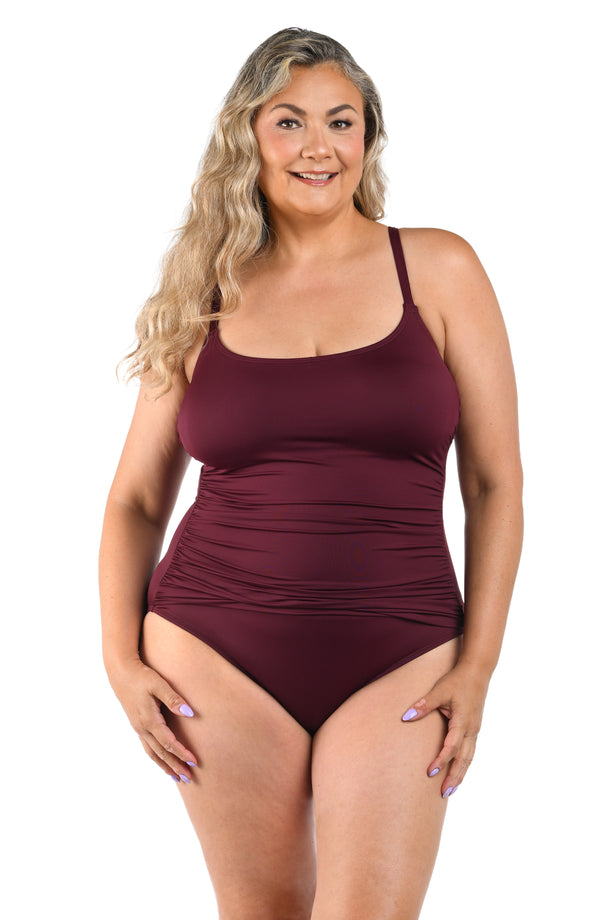 Front image of plus size model wearing a solid dark cherry colored one-piece swimsuit featuring thin over the shoulder straps and a ruched body. 