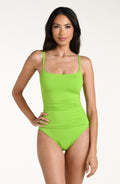 Woman wearing an apple green one piece swimsuit set against a white background.