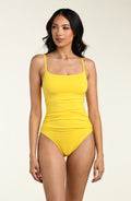 Woman wearing a yellow one piece swimsuit against a white background.