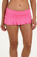 Front image of model wearing a rose pink colored swim skirt with a ruched waistband and a flared ruffle hem. 