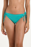 Front image of model wearing a calypso (turquoise) colored bikini bottoms with adjustable side ties accented with gold tips.