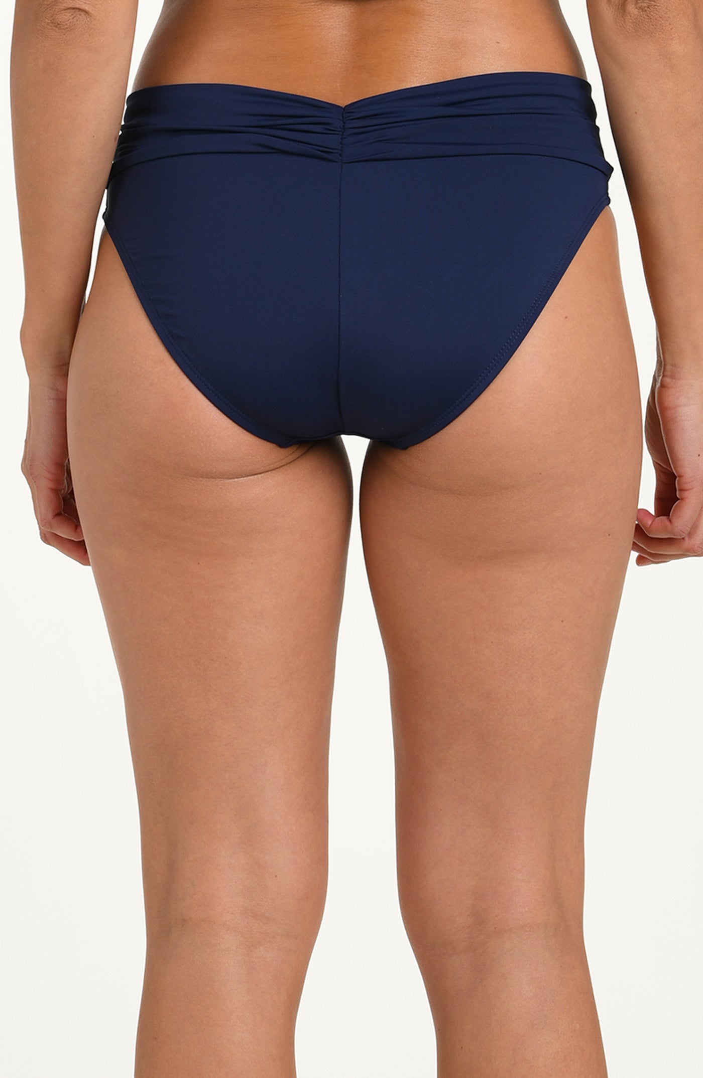 Back image of model wearing an indigo (navy blue) colored bikini bottoms with a wide, ruched waistband and moderate rear coverage.