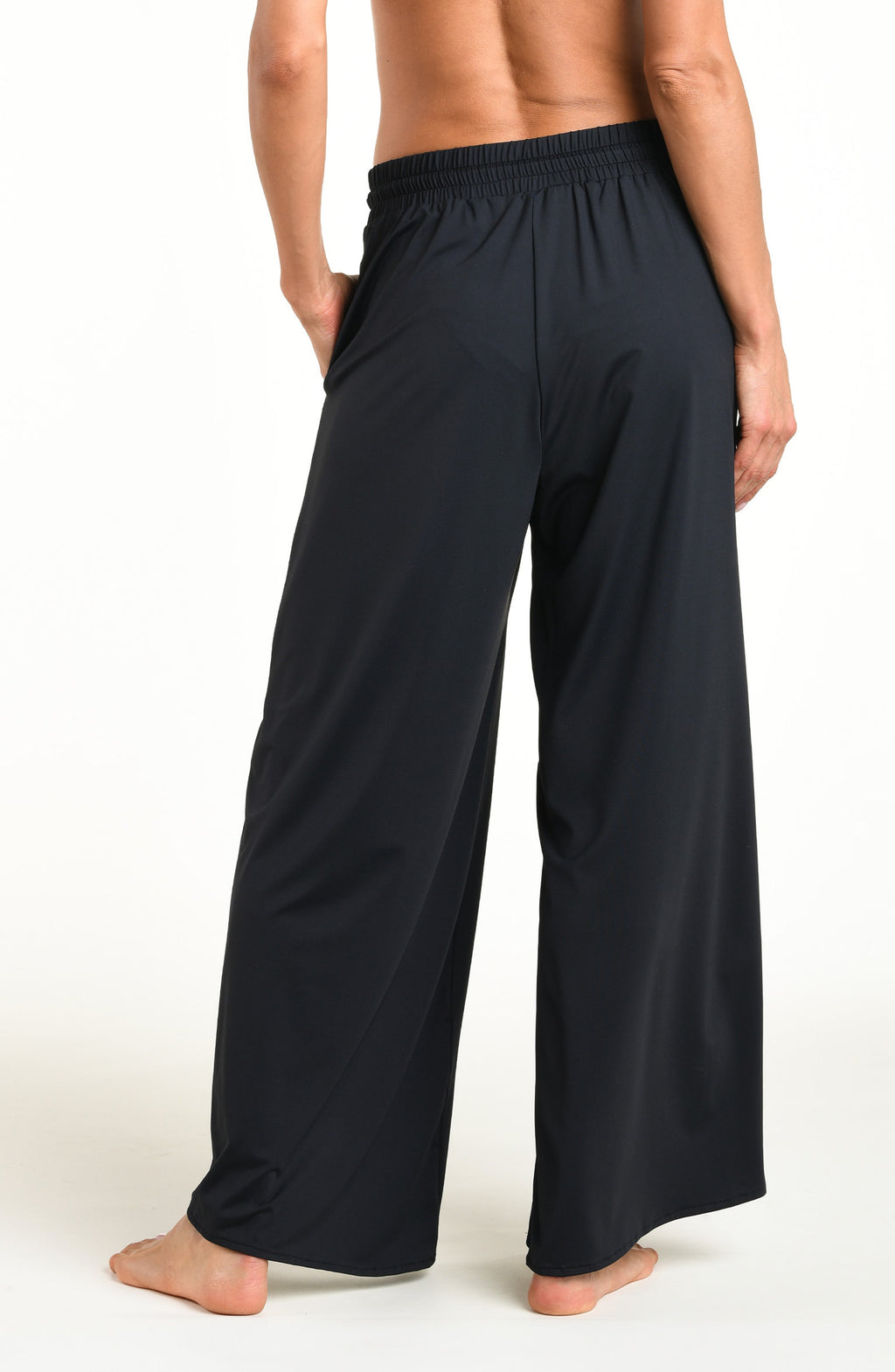 Woman wearing solid black beach pants against a white background. 