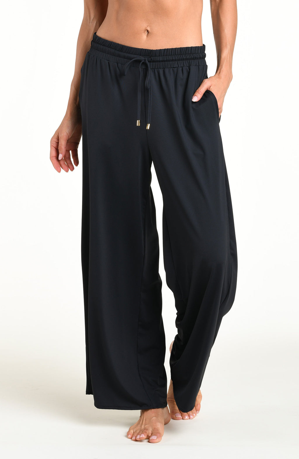 Woman wearing solid black beach pants against a white background. 