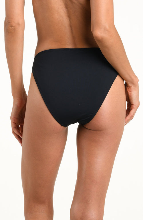 Woman wearing a solid black bikini bottom against a white background. 