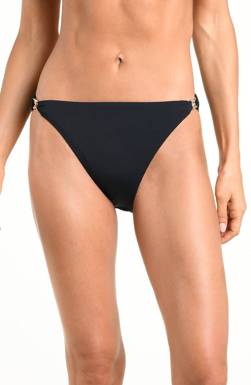 Woman wearing a solid black bikini bottom against a white background. 