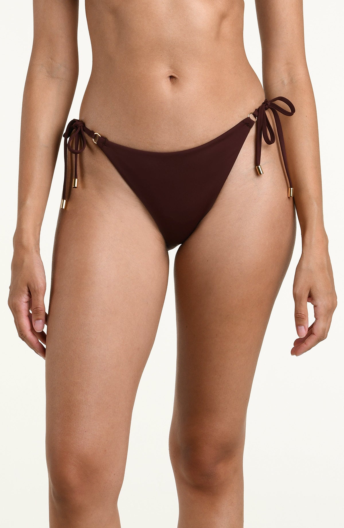 Woman wearing a solid java brown bikini bottom with side ties against a white background. 