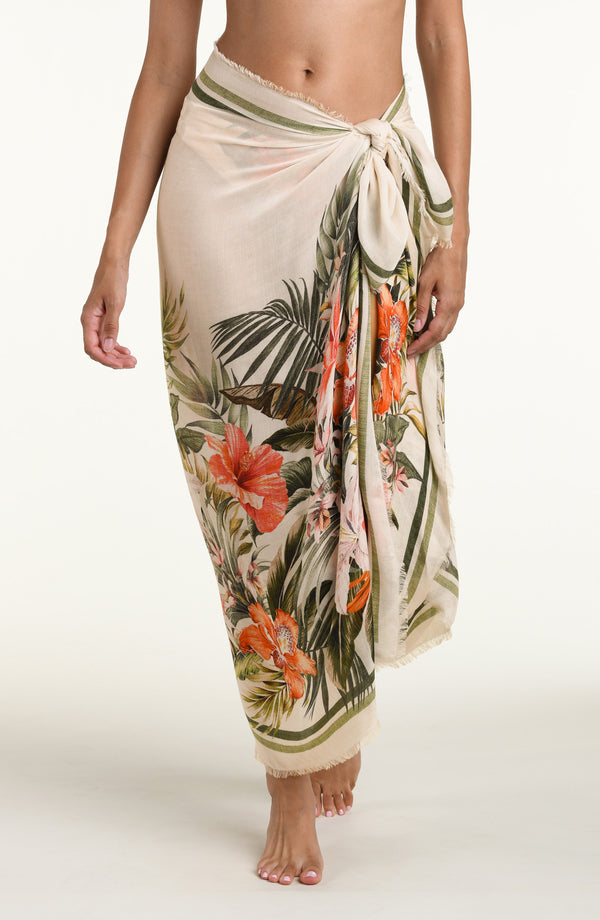 Woman wearing a white multicolored pareo wrap cover up against a white background. 