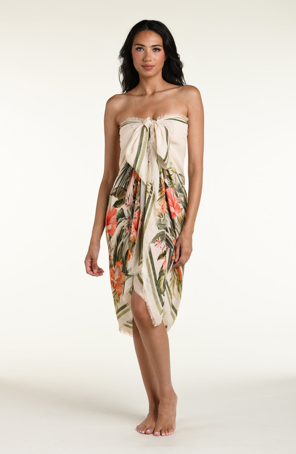 Woman wearing a white multicolored pareo wrap cover up against a white background. 