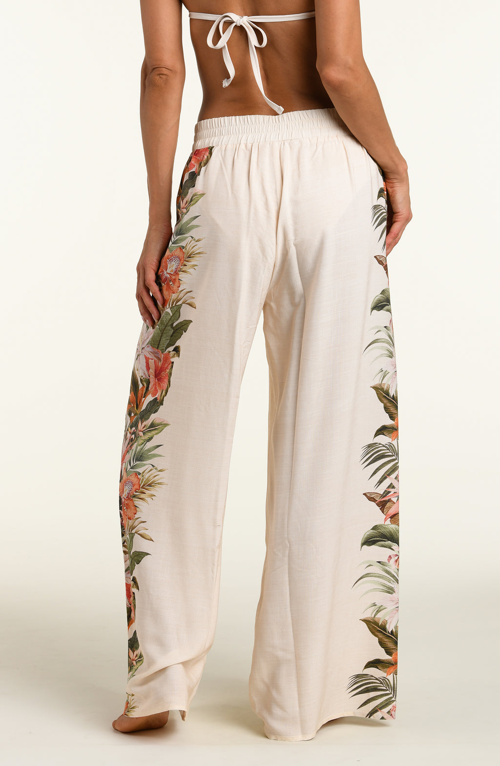 Woman wearing a white multicolored pants against a white background. 