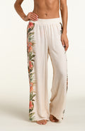Woman wearing a white multicolored pants against a white background. 