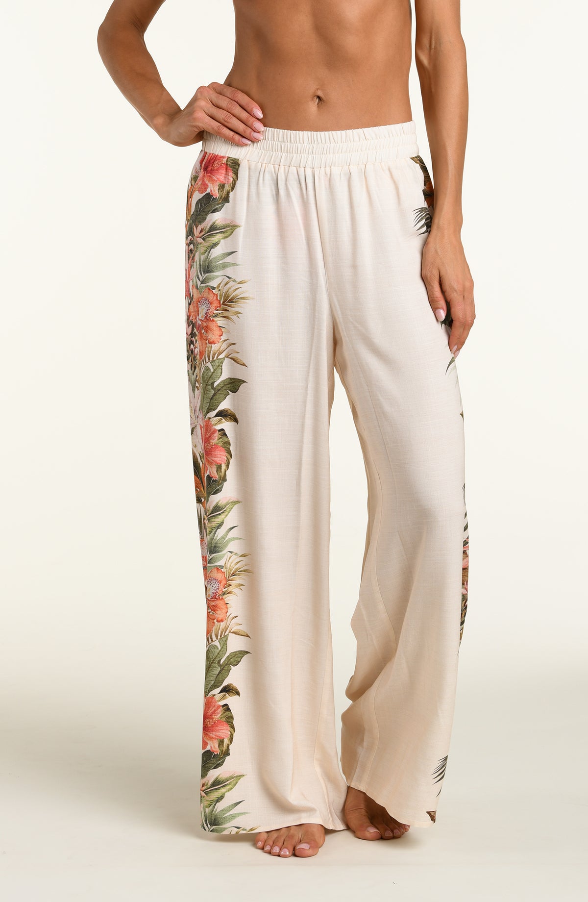 Woman wearing a white multicolored pants against a white background. 