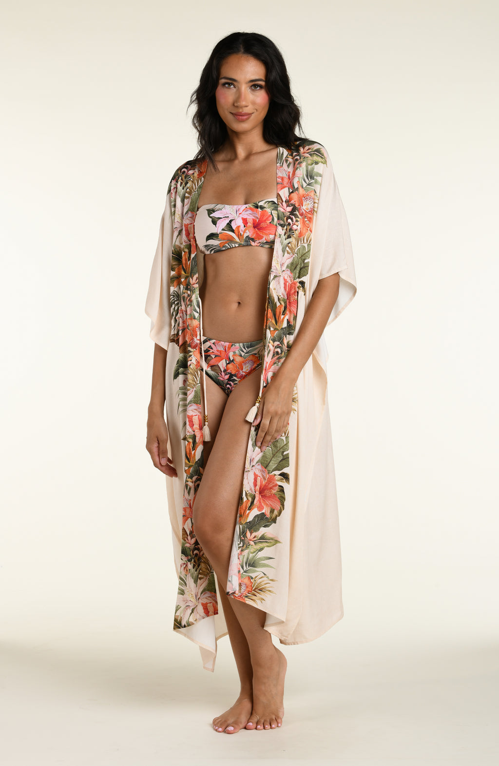 Woman wearing a champagne multicolored kimono cover up against a white background. 
