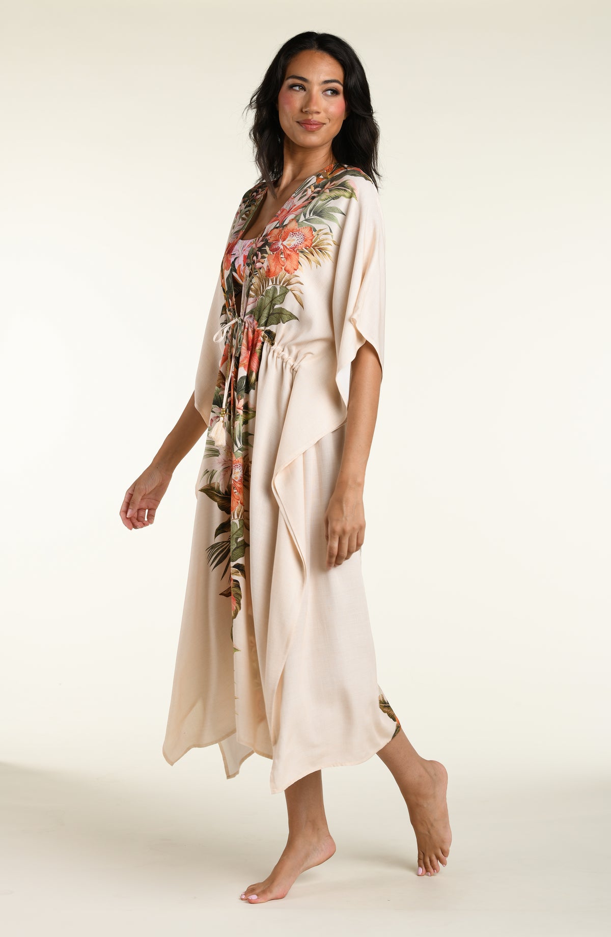 Woman wearing a champagne multicolored kimono cover up against a white background. 