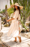 Woman wearing a champagne multicolored kimono cover up in an outside setting. 