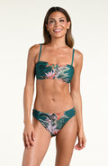 A woman modeling a two-piece bikini with a tropical floral print in teal green, featuring a halter-style top and matching bottoms, against a white background.