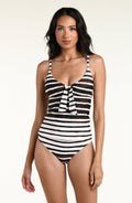 A woman modeling a tankini top and matching bottom with horizontal brown and white stripes against a plain light background.