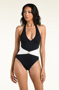 A woman modeling a one-piece swimsuit with a black color-blocked design, featuring a white sash at the waist with a small pearl detail, set against a white background.