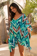 Woman wearing a teal multicolored tunic cover up in an outdoor setting. 