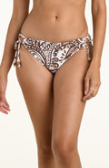 A close-up of a model wearing a pair of white bikini bottoms with a brown paisley pattern and side ties, shown against a plain light background.