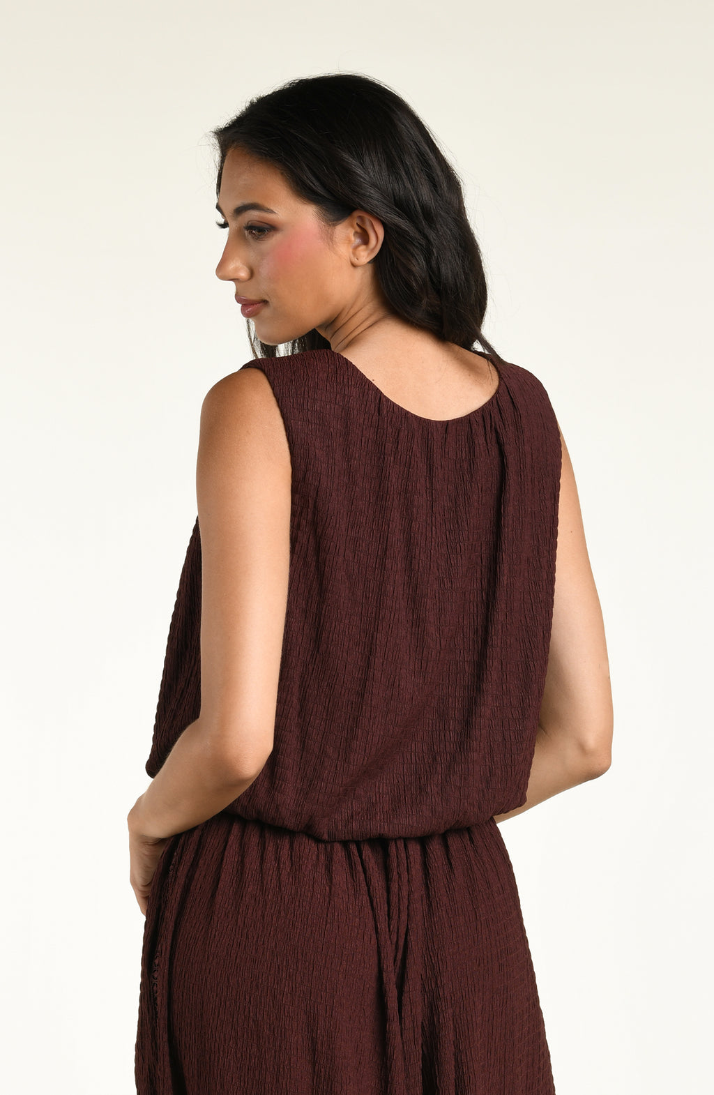 Woman wearing a java brown colored sleeveless top against a white background. 