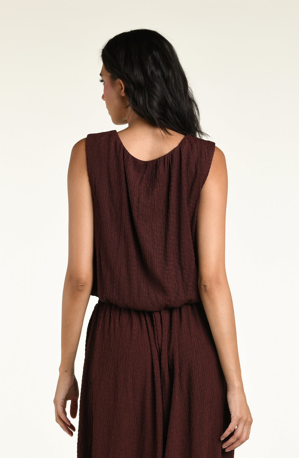 Woman wearing a java brown colored sleeveless top against a white background. 