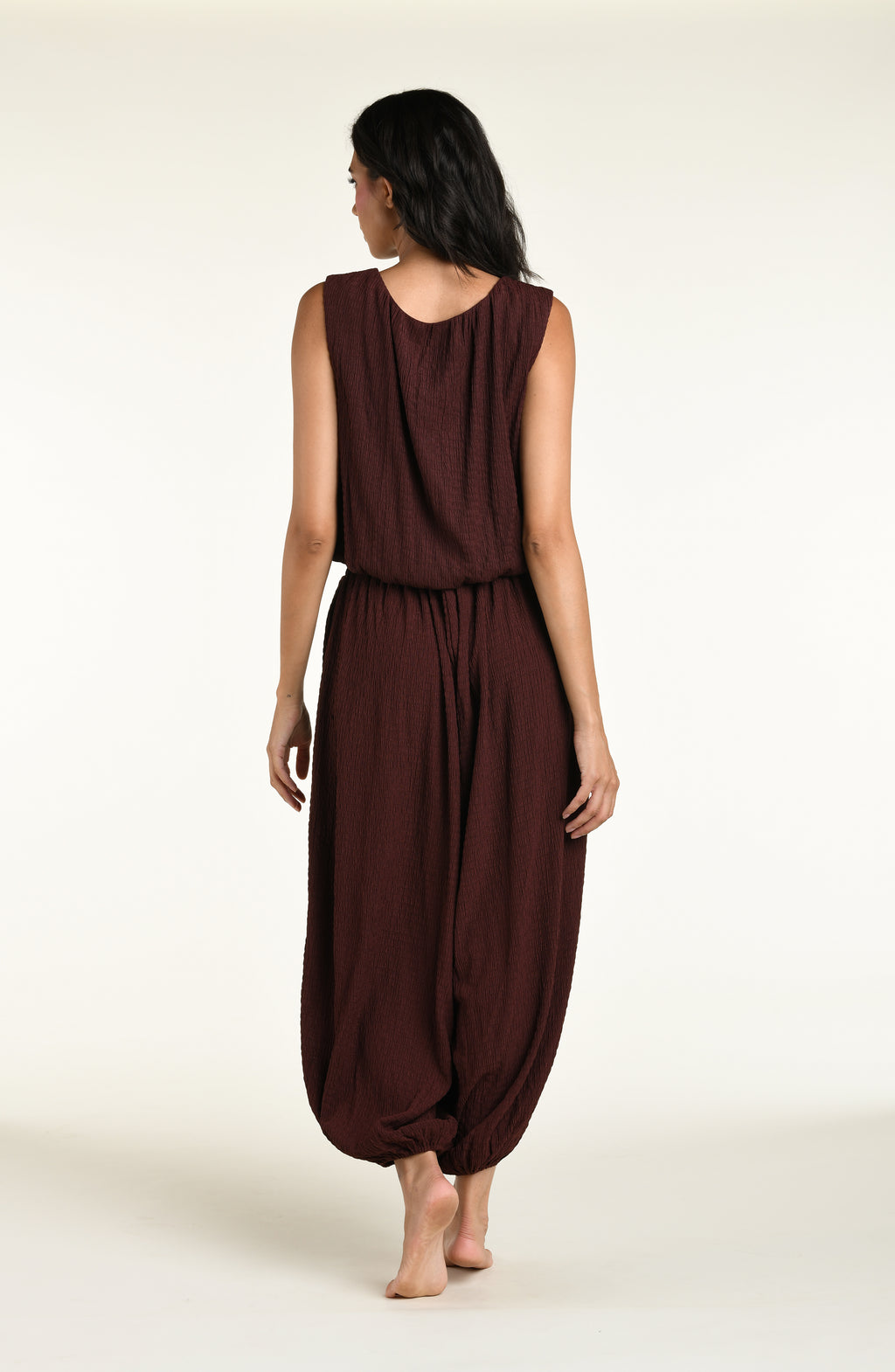 Woman wearing a java brown colored sleeveless top and matching pants against a white background. 