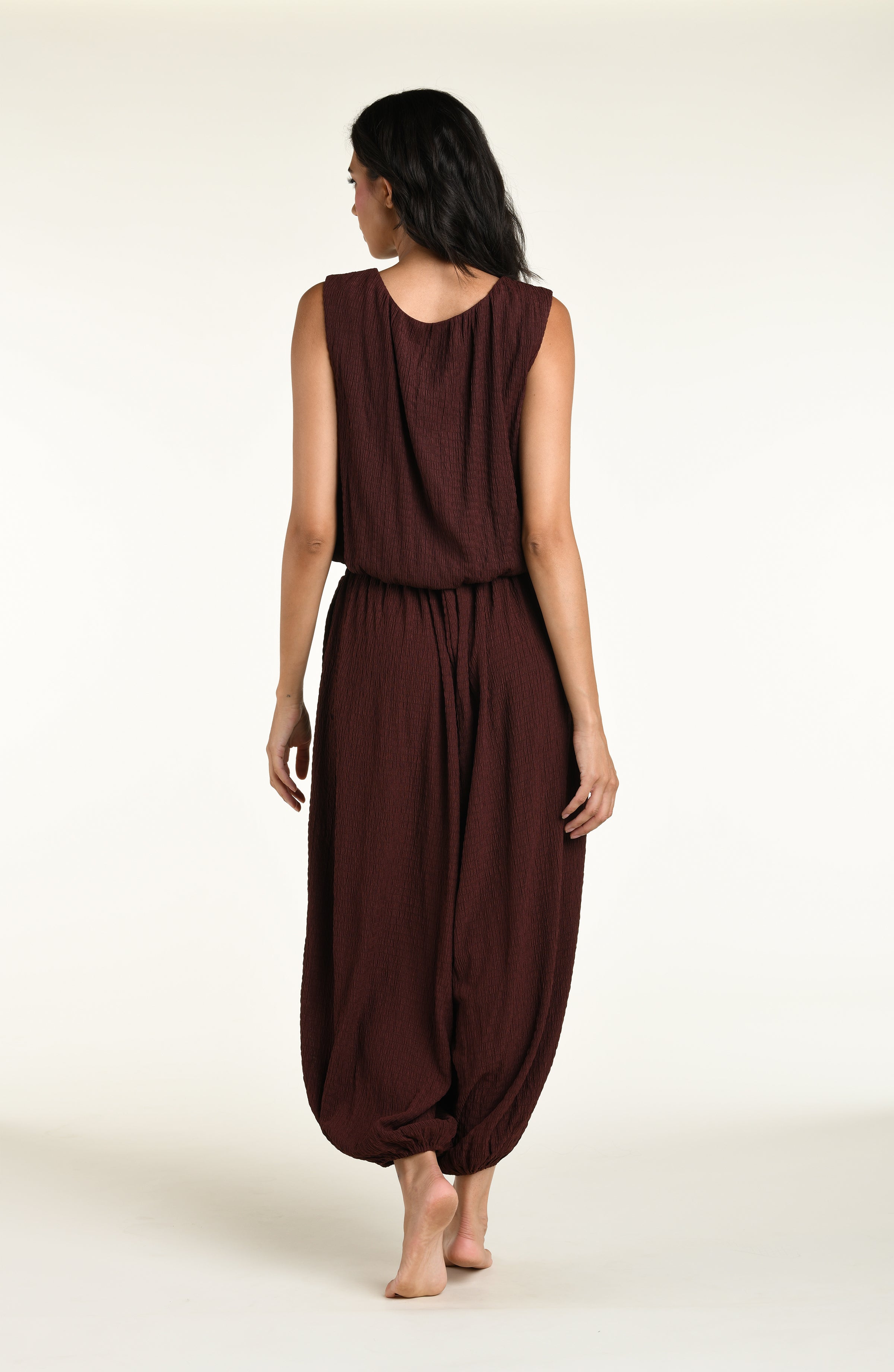 Woman wearing a java brown colored sleeveless top and matching pants against a white background. 