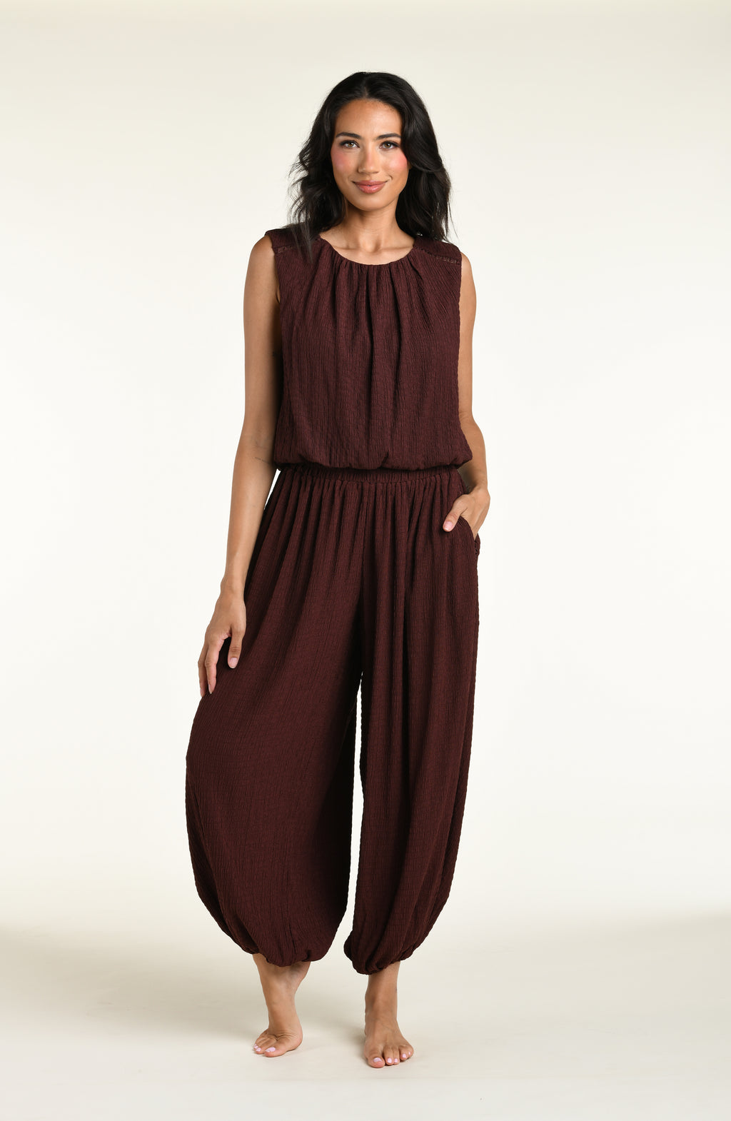 Woman wearing a java brown colored sleeveless top and matching pants against a white background. 