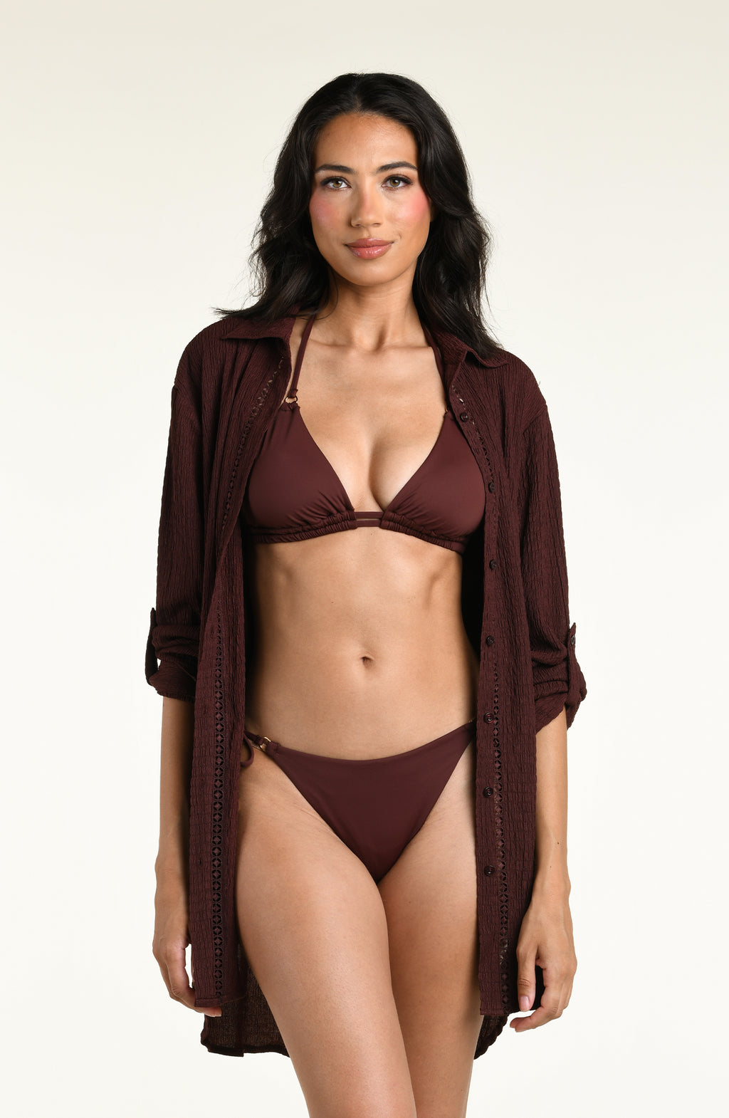 Woman wearing a java brown colored long sleeve cover up top with a matching bikini top and bottom underneath, against a white background. 