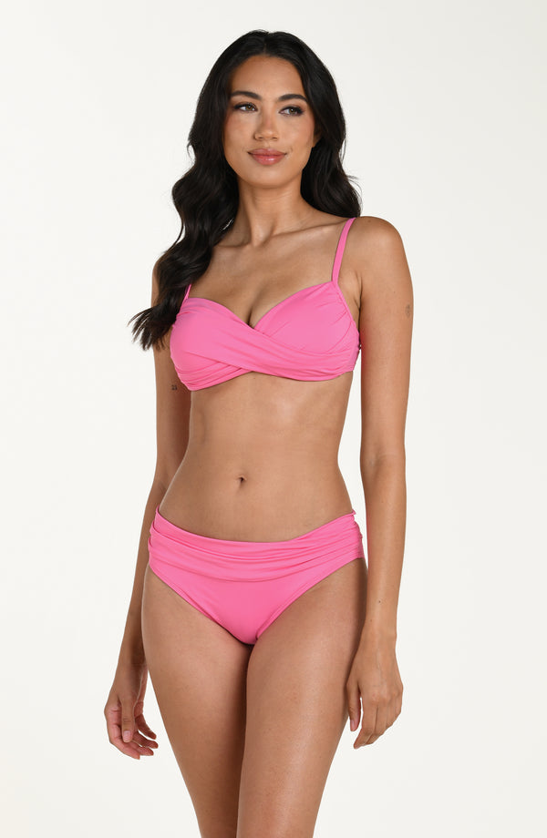 Front image of model wearing a rose pink colored bikini top with adjustable thin straps and a wrap-style front. This is paired with matching bikini bottoms.