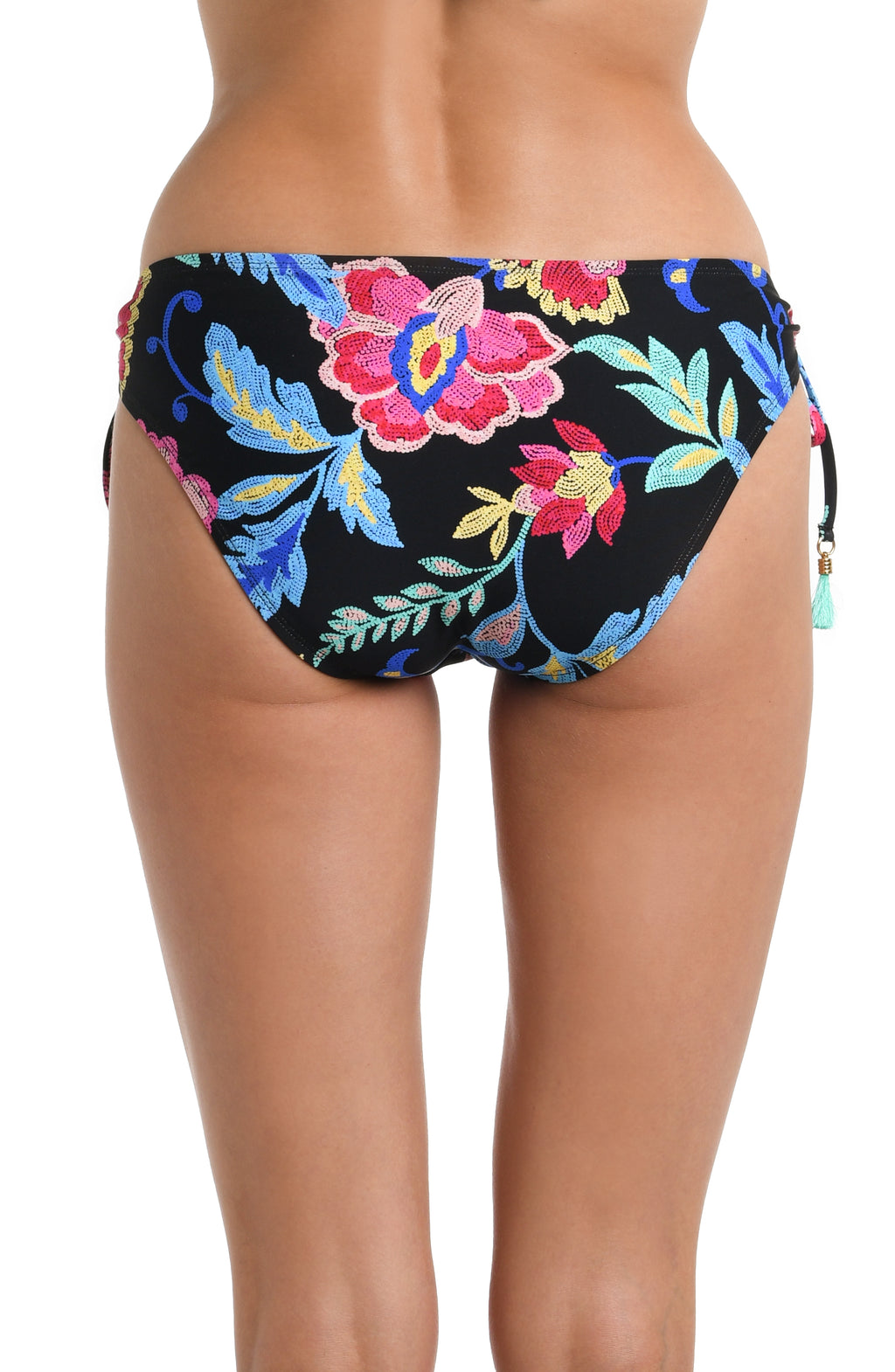 Back image of model wearing a black, pink, and blue multicolored floral patterned hipster bikini swimsuit bottom featuring a side ties adorned with tassels and moderate rear coverage.