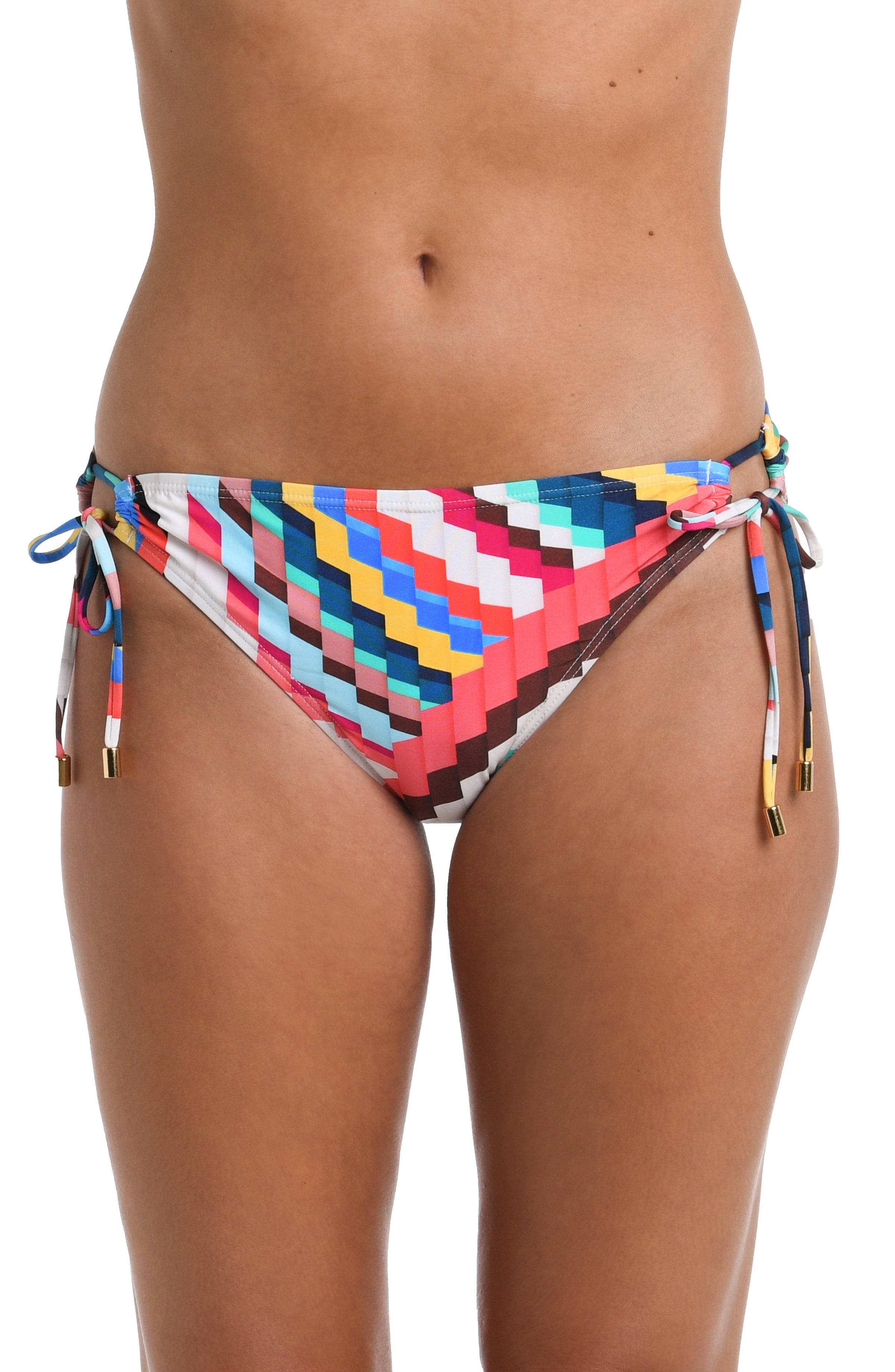 Close-up front image of model wearing a vibrant multi-colored geometric printed bikini swimsuit bottom featuring a hipster cut and side ties adorned with tassels.