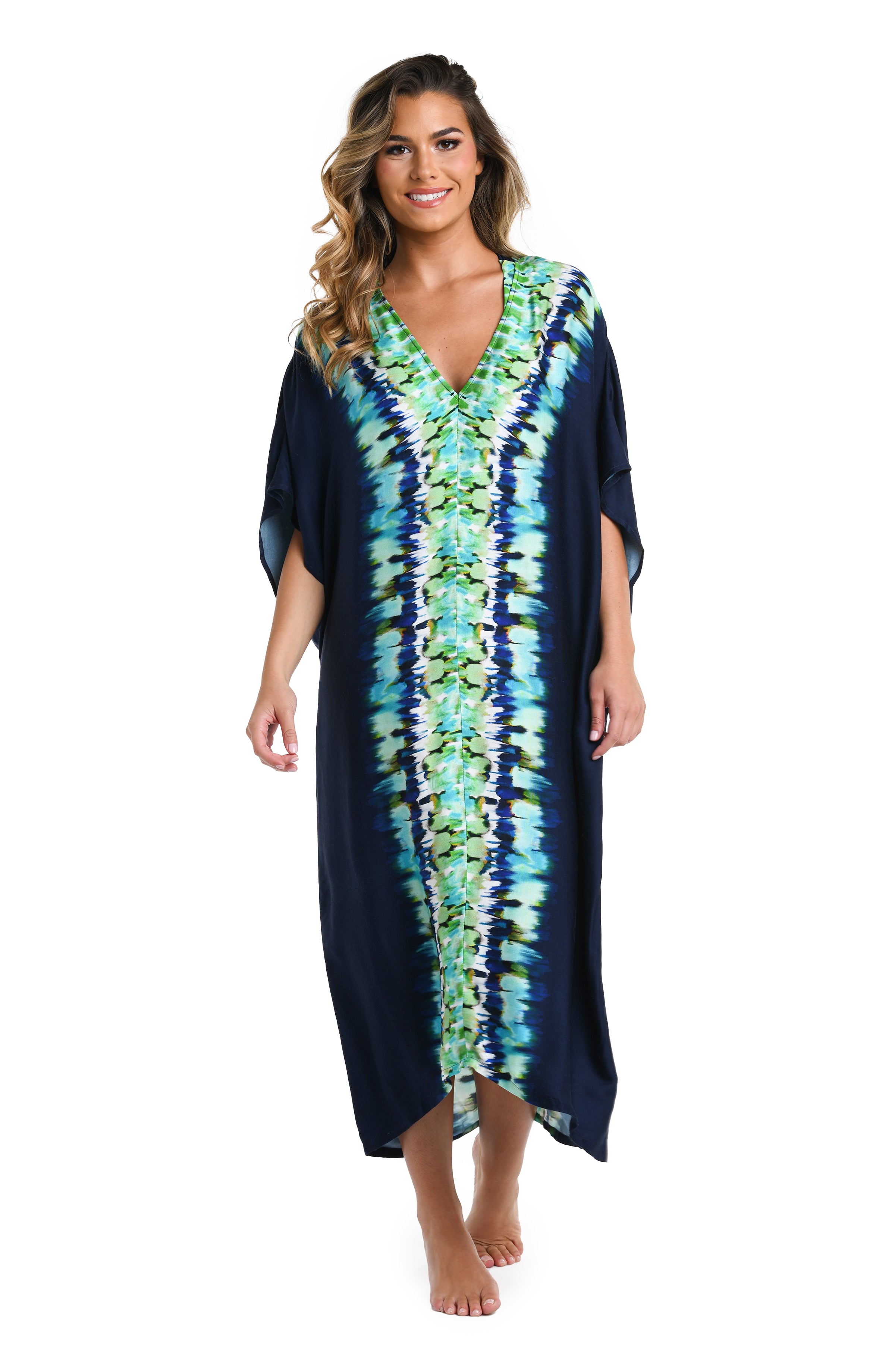 Full body front image of model wearing an indigo and blue tie-dye colored caftan cover-up featuring a v-neckline, dolman sleeves, and a long cut.