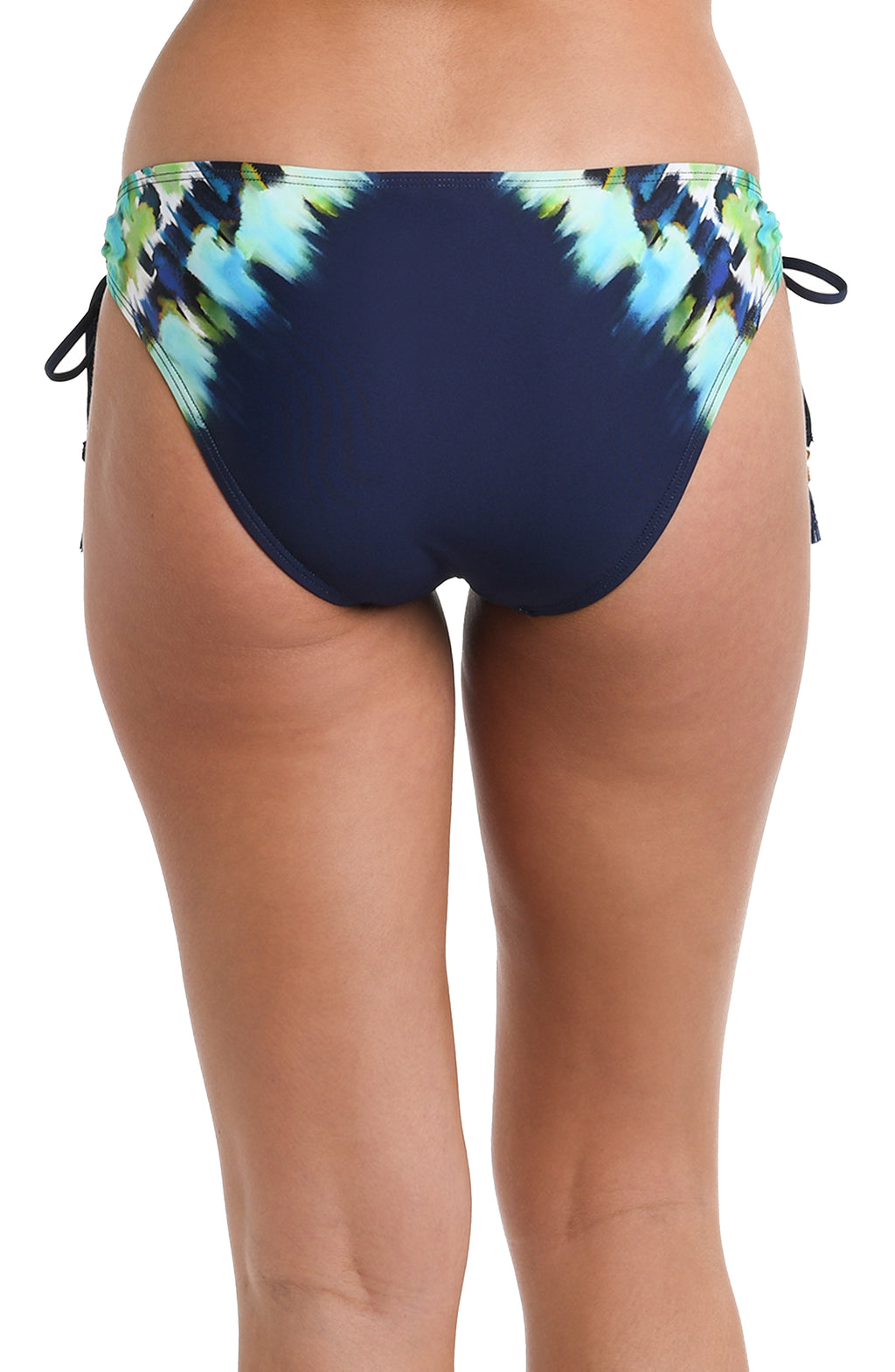 Back image of model wearing an indigo and blue tie-dye colored bikini swimsuit bottom featuring side ties adorned with tassels and moderate rear coverage.