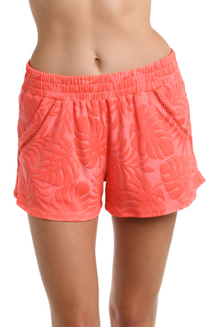 Model is wearing a coral colored palm printed Beach Shorts