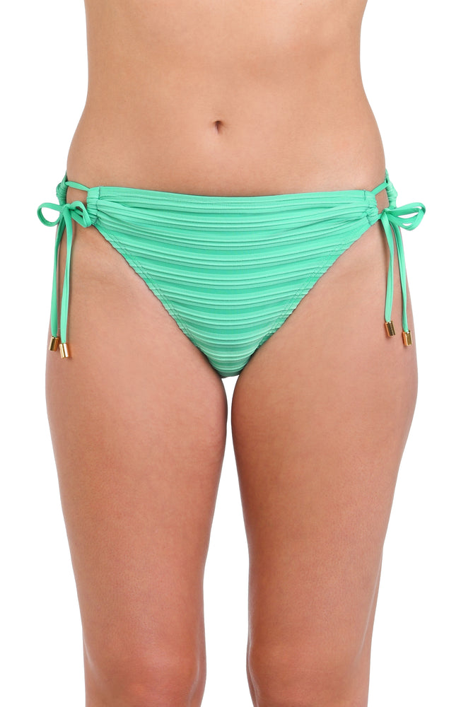 Model is wearing a textured seafoam green colored side tie hipster bikini bottom with clean textured horizontal lines.