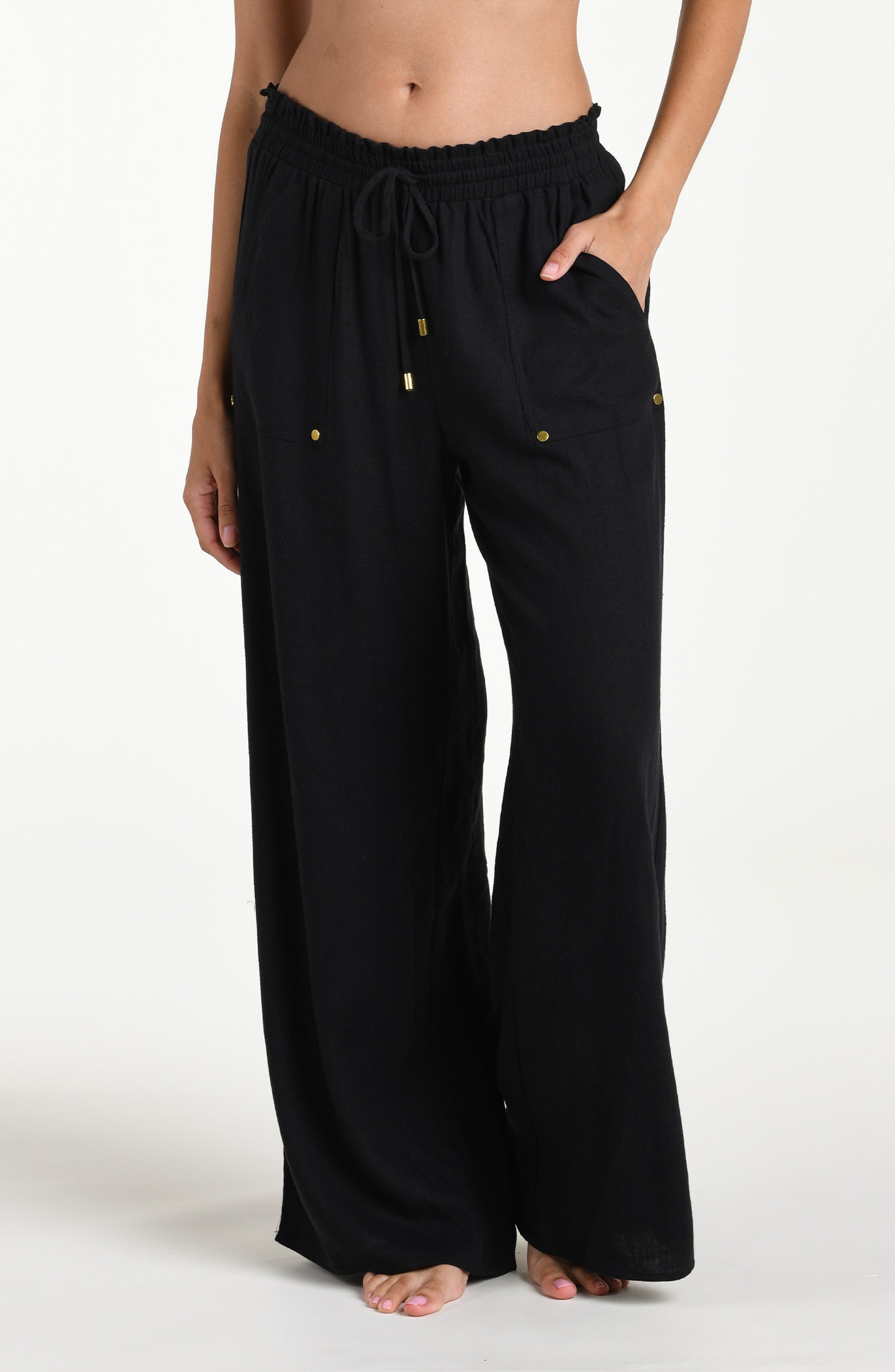 Black wide-leg pants with gold buttons against a white background