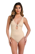 Model is wearing a solid taupe (sandy beige) colored plunge one piece swimsuit.