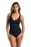 Front image of model wearing a one piece swimsuit featuring over the shoulder straps and a shirred body. 