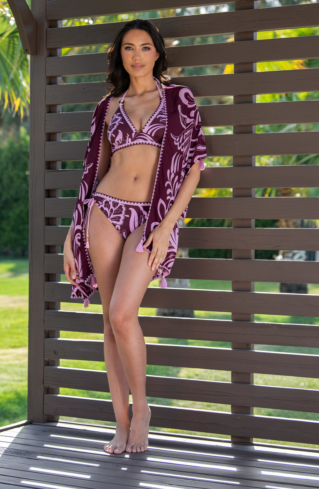 Lifestyle image of a model wearing a dark cherry and pink tropical patterned open front kimono cover up. 