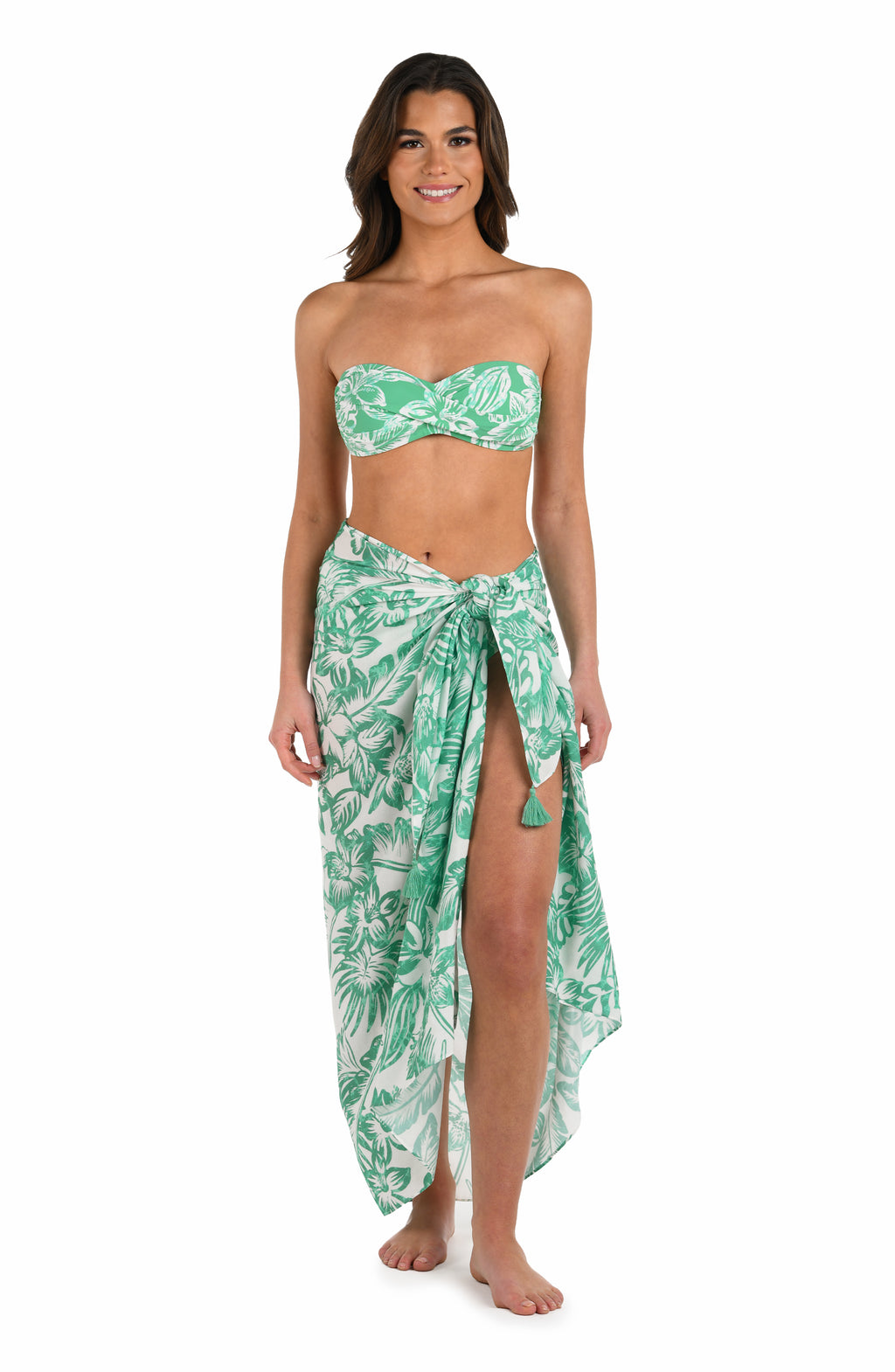 Full body front image of model wearing a green and white tropical-print pareo wrap cover up. 