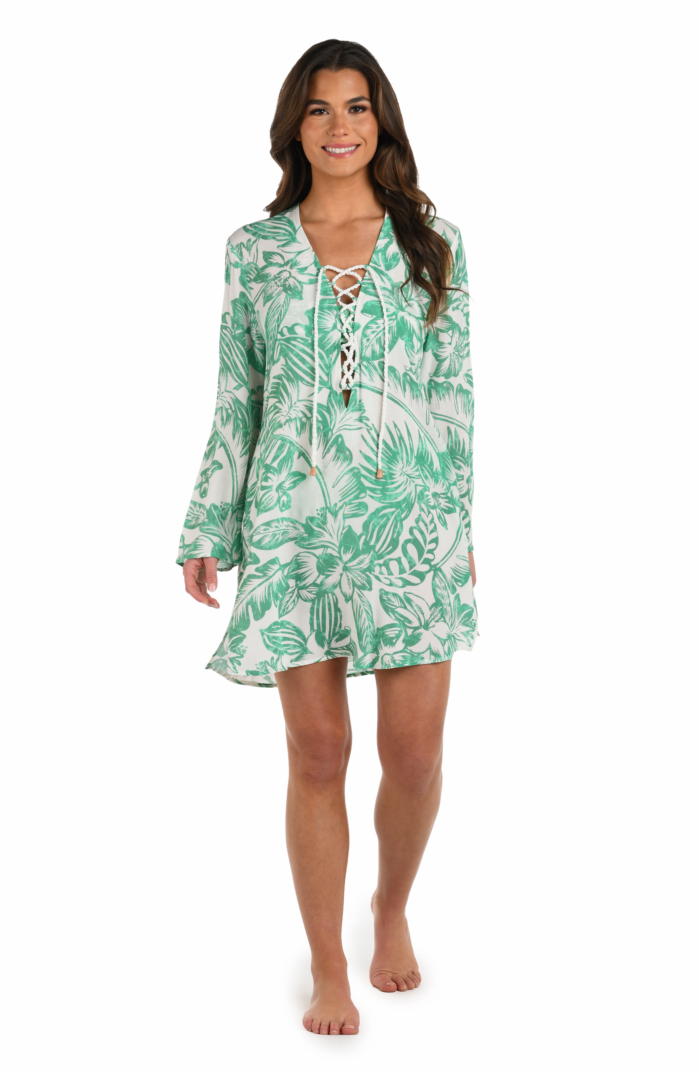 Full body front image of model wearing a green and white floral-printed long-sleeve tunic with a lace-up neckline and side pockets.
