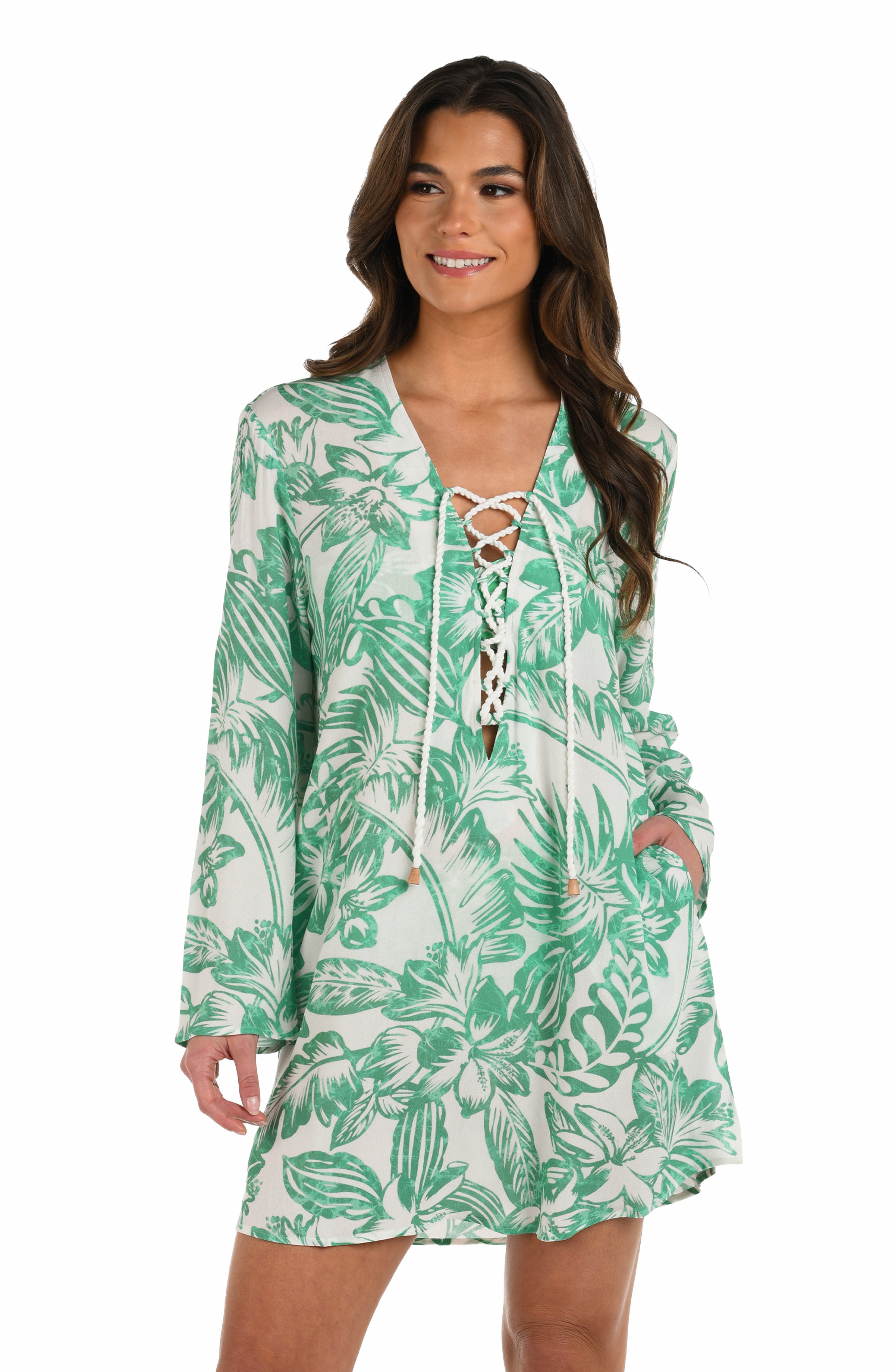 Front image of model wearing a green and white floral-printed long-sleeve tunic with a lace-up neckline and side pockets.