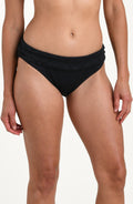 Front image of model wearing a black jacquard fabric hipster swimsuit bottom featuring a shirred front band. 