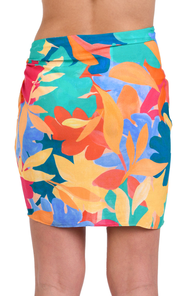 Model is wearing an orange, pink, blue, and aqua multicolored tropical patterned short pareo wrap cover up.