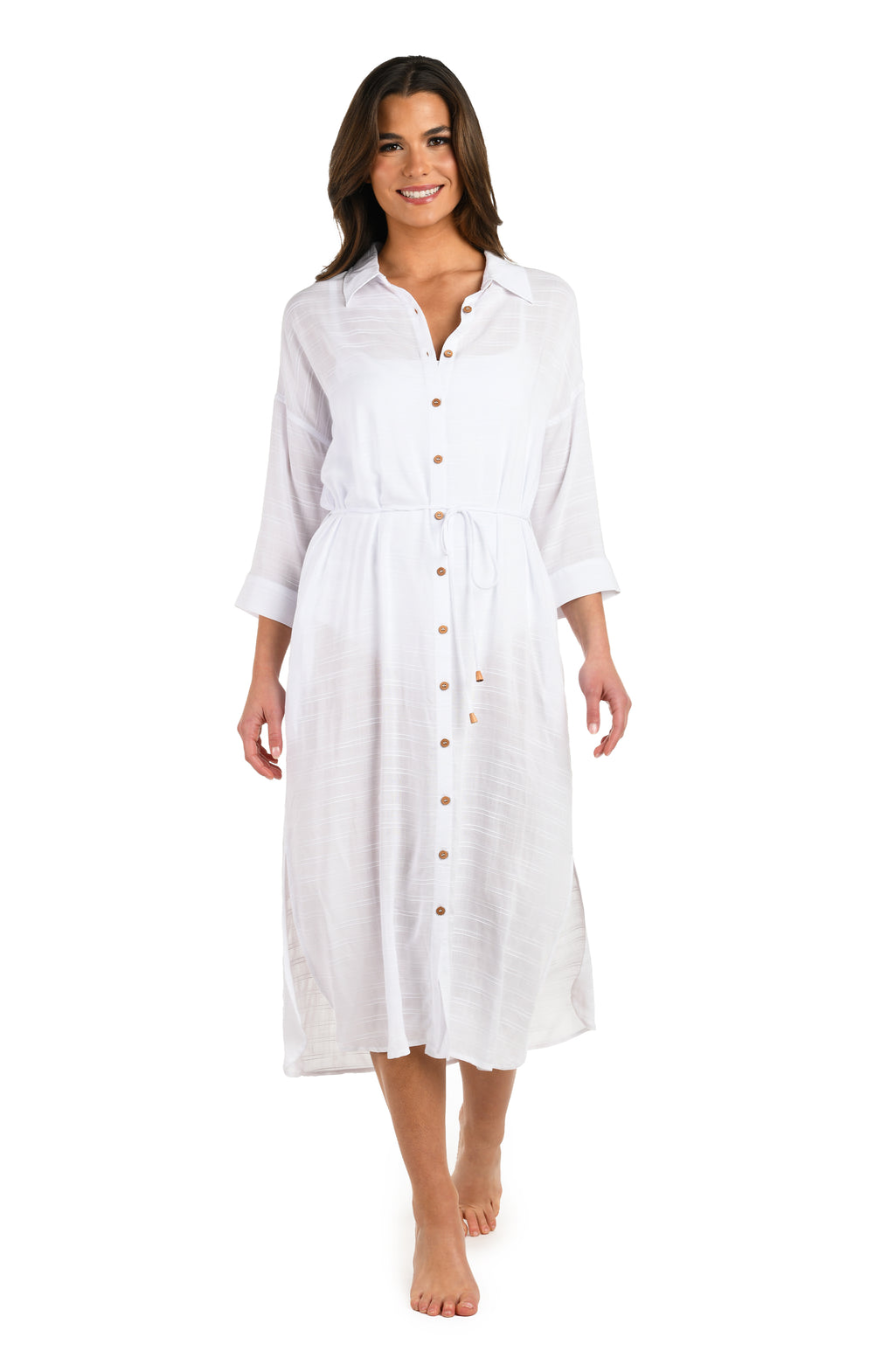 Full body front image of model wearing a white, long-sleeve, button-down midi beach cover-up dress with a drawstring waist and side slits.