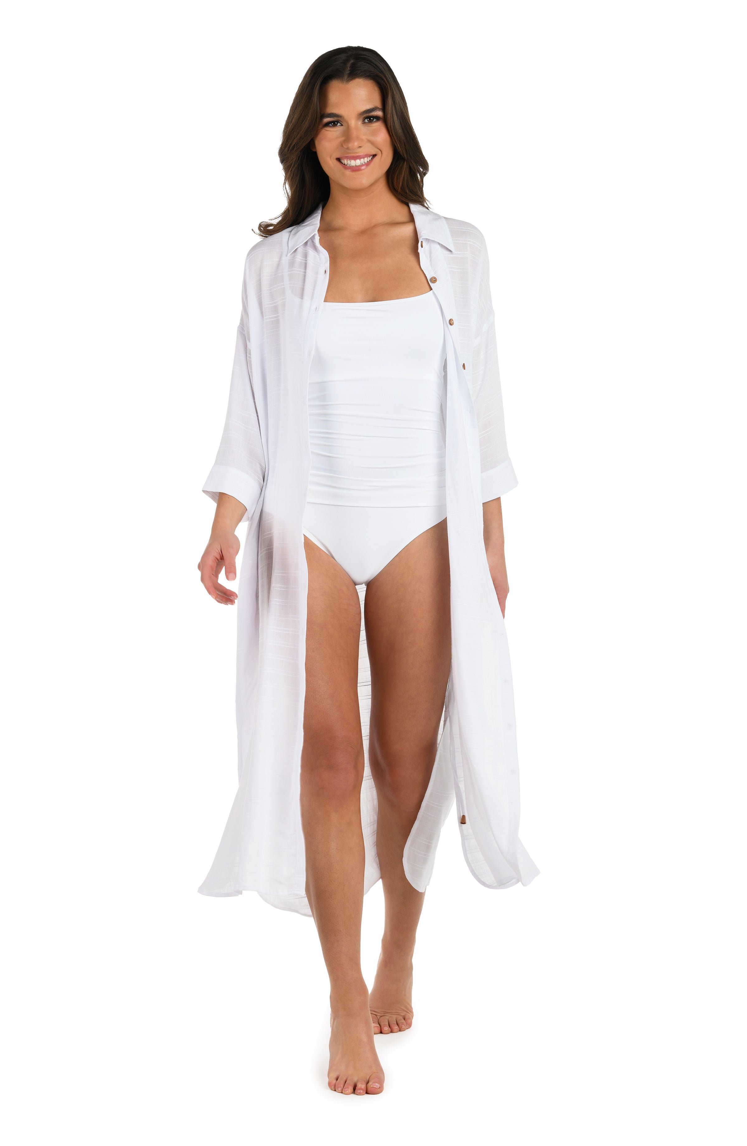 Full body front image of model wearing a white, long-sleeve, button-down midi beach cover-up dress with a drawstring waist and side slits.